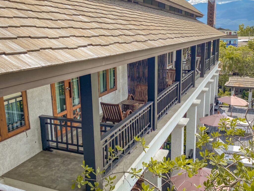 Deluxe balcony room at The Balcony Chiang Mai with a spacious outdoor balcony offering seating, lush greenery, and a stunning view of the city and mountains